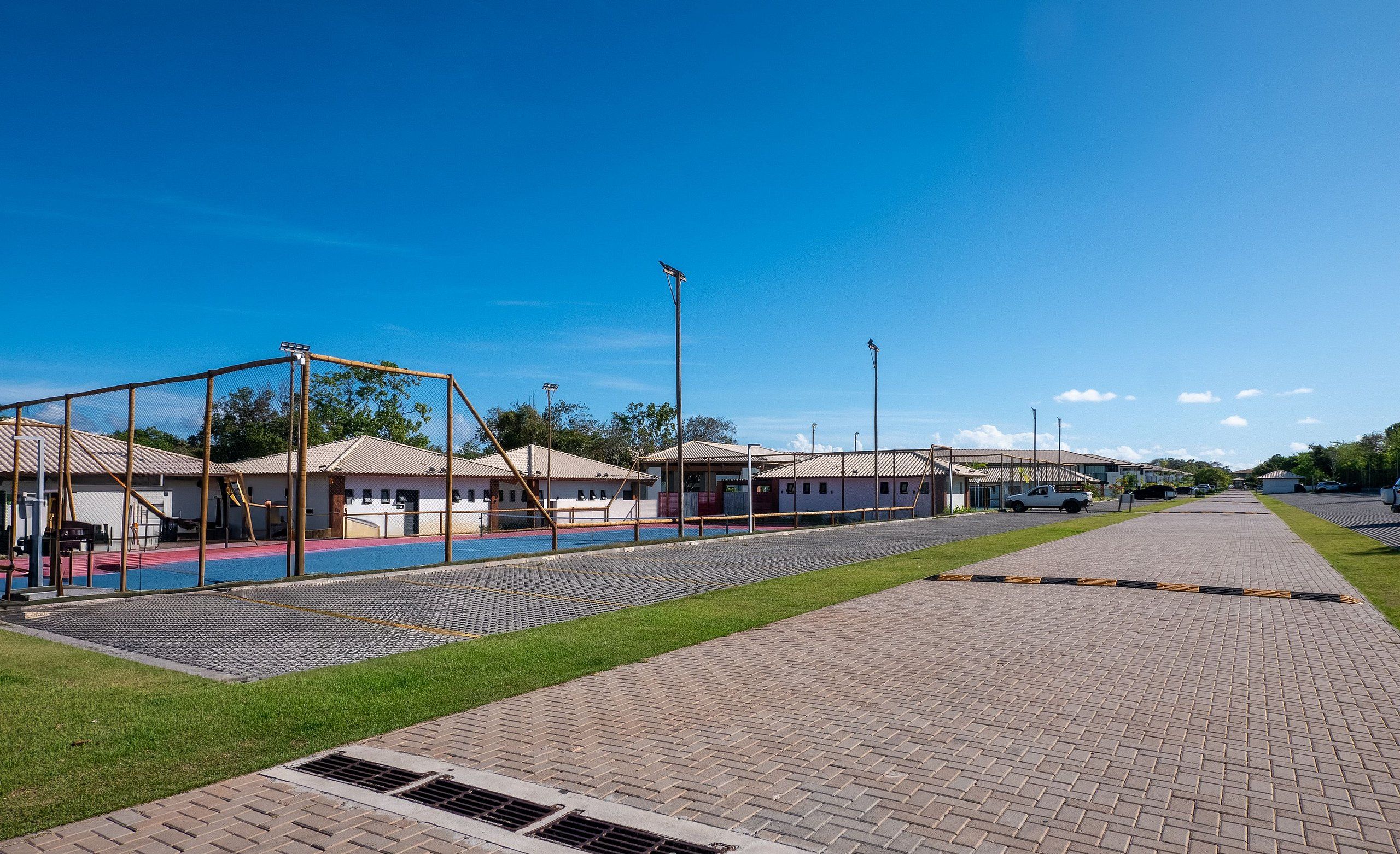 Zona de juegos con columpios y un área vallada, rodeada de edificios con tejados de tejas.