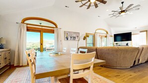 A spacious living area with a wooden dining table, white chairs, a beige sofa, and a ceiling fan. - CH50: The Sweet Pelican, 4BR home with Shared Pool- pet friendly (Kill Devil Hills)