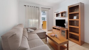 Un saló modern amb un sofà, una taula de centre, un moble de televisió i una prestatgeria de fusta.