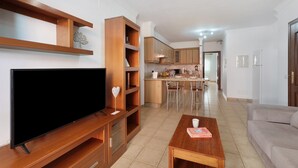 Un saló amb un televisor de pantalla plana, prestatges de fusta, una taula de centre i un sofà.