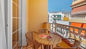 A balcony with wicker chairs, a table, a book, and a glass of drink.