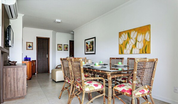 A dining area with a table set for four, surrounded by wicker chairs with floral upholstery.