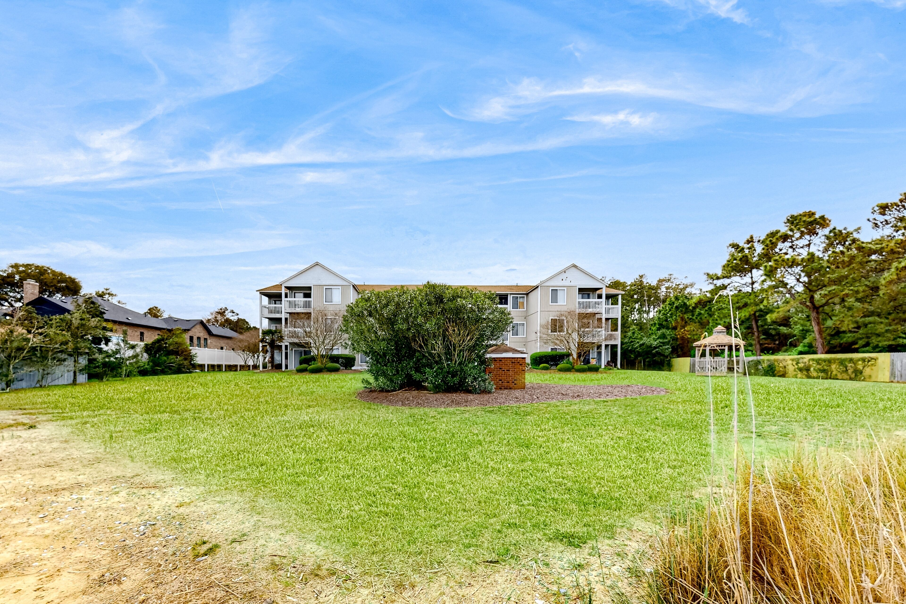 A residential area with two apartment buildings, a well-maintained lawn, and a gazebo.