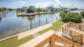 A waterfront property with a wooden deck, a dock, and a boat.