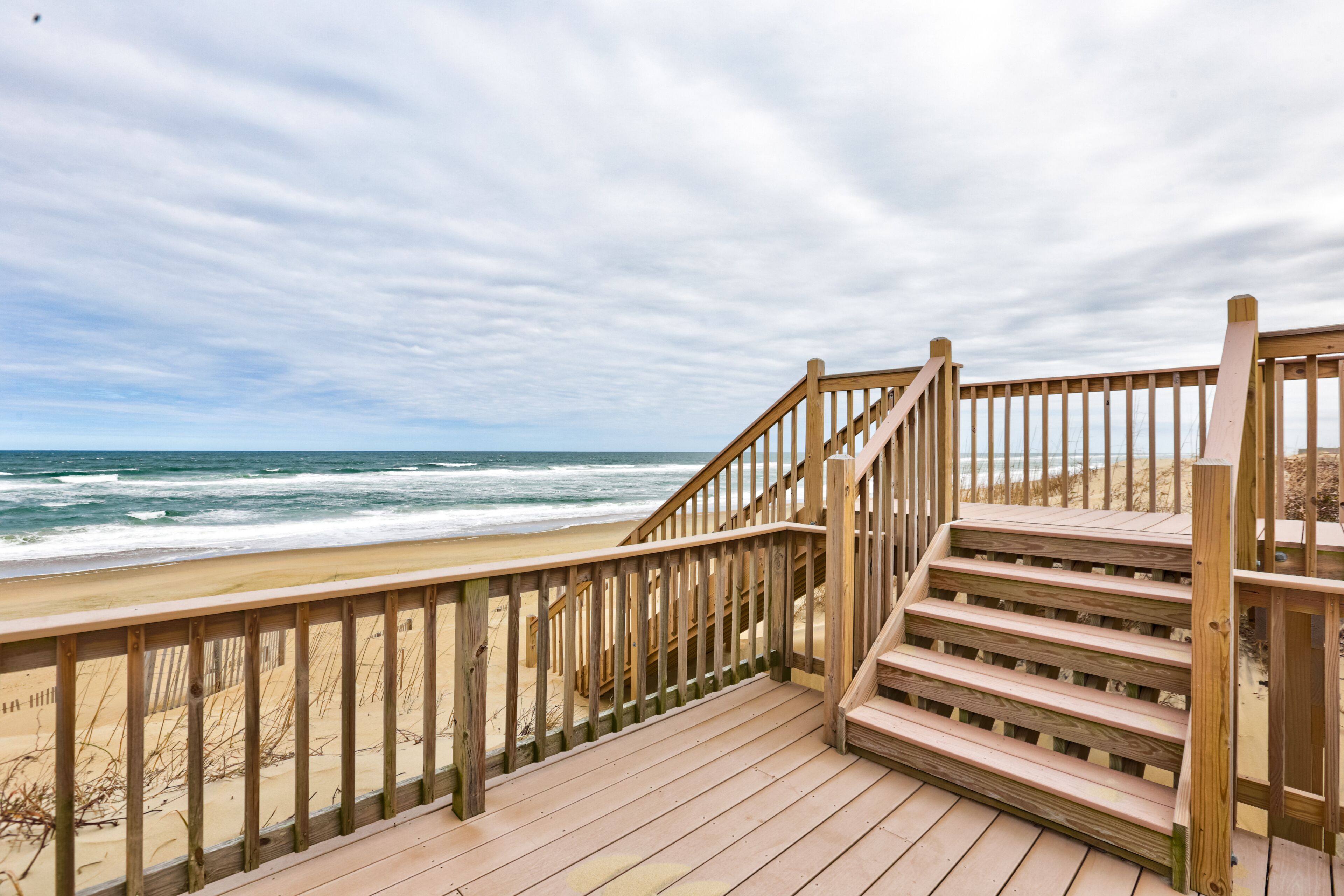 A wooden staircase leading to a beach with a wooden railing.