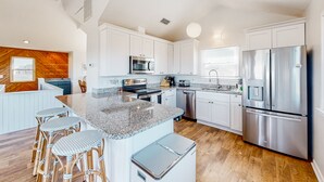 A modern kitchen with white cabinets, stainless steel appliances, and a granite countertop.