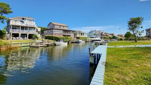 A canal with boats docked, waterfront houses, and a wooden dock.