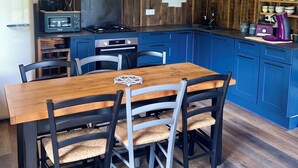 A kitchen with a wooden table and chairs, a stove, and blue cabinets.