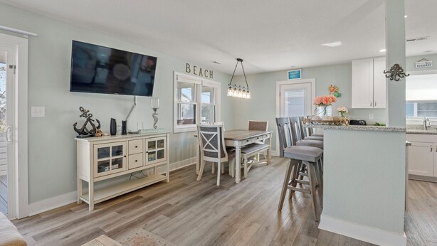 A modern kitchen with a dining area, a TV mounted above the counter, and a sign that reads "BEACH".