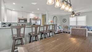 A modern kitchen with white cabinets, stainless steel appliances, and a dining area with a wooden table and chairs.