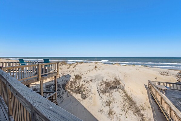 A beach view with a wooden deck and chairs. - Large 3BR Oceanfront | Deck | Tennis | W/D (Nags Head)