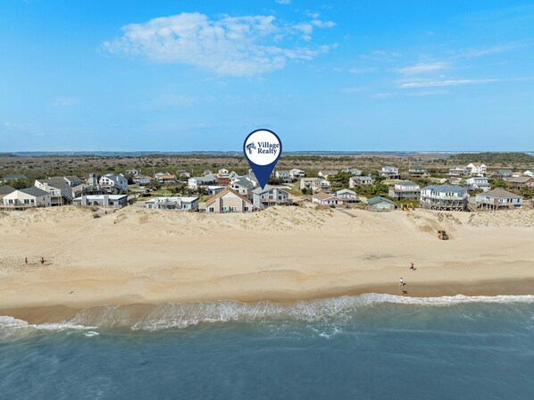 A beachside village with houses, a beach, and a clear sky. - Large 3BR Oceanfront | Deck | Tennis | W/D (Nags Head)