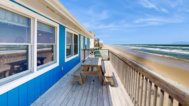 Une terrasse en bois offrant une vue sur la plage et l’océan.
