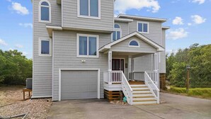 A two-story house with a front porch, a staircase, and a garage. - SH03: SS OBX | Sunny Home| Dog-Friendly | Private Pool (Southern Shores)