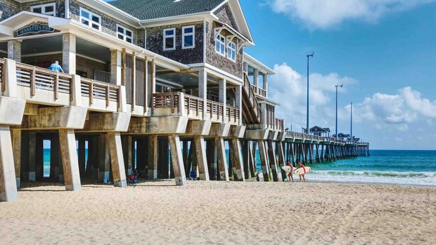 A beachfront property with a pier extending into the ocean, featuring multiple balconies and a covered area. - SH03: SS OBX | Sunny Home| Dog-Friendly | Private Pool (Southern Shores)