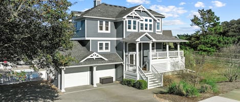 A two-story house with a porch, a garage, and a well-maintained lawn.