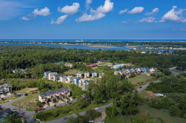 An aerial view of a residential area with houses, roads, and a body of water in the background. - CH937: Sounds About Wright, 4BR remodeled home, game room, firepit, W/D (Kill Devil Hills)