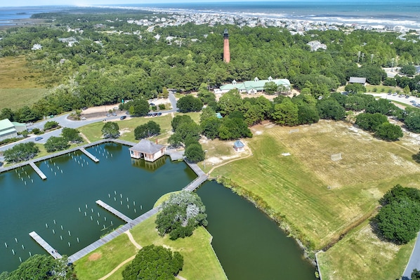 Luchtbeeld van een park met een vuurtoren, een vijver en omliggend groen.