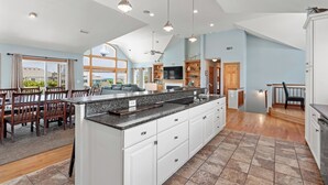 A spacious kitchen with a large island, white cabinetry, and a view of the outdoors. - 10BR | Private Pool | Hot Tub | Elevator (Corolla)