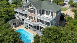 A multi-story house with a large balcony, a swimming pool, and a well-maintained lawn. - 10BR | Private Pool | Hot Tub | Elevator (Corolla)