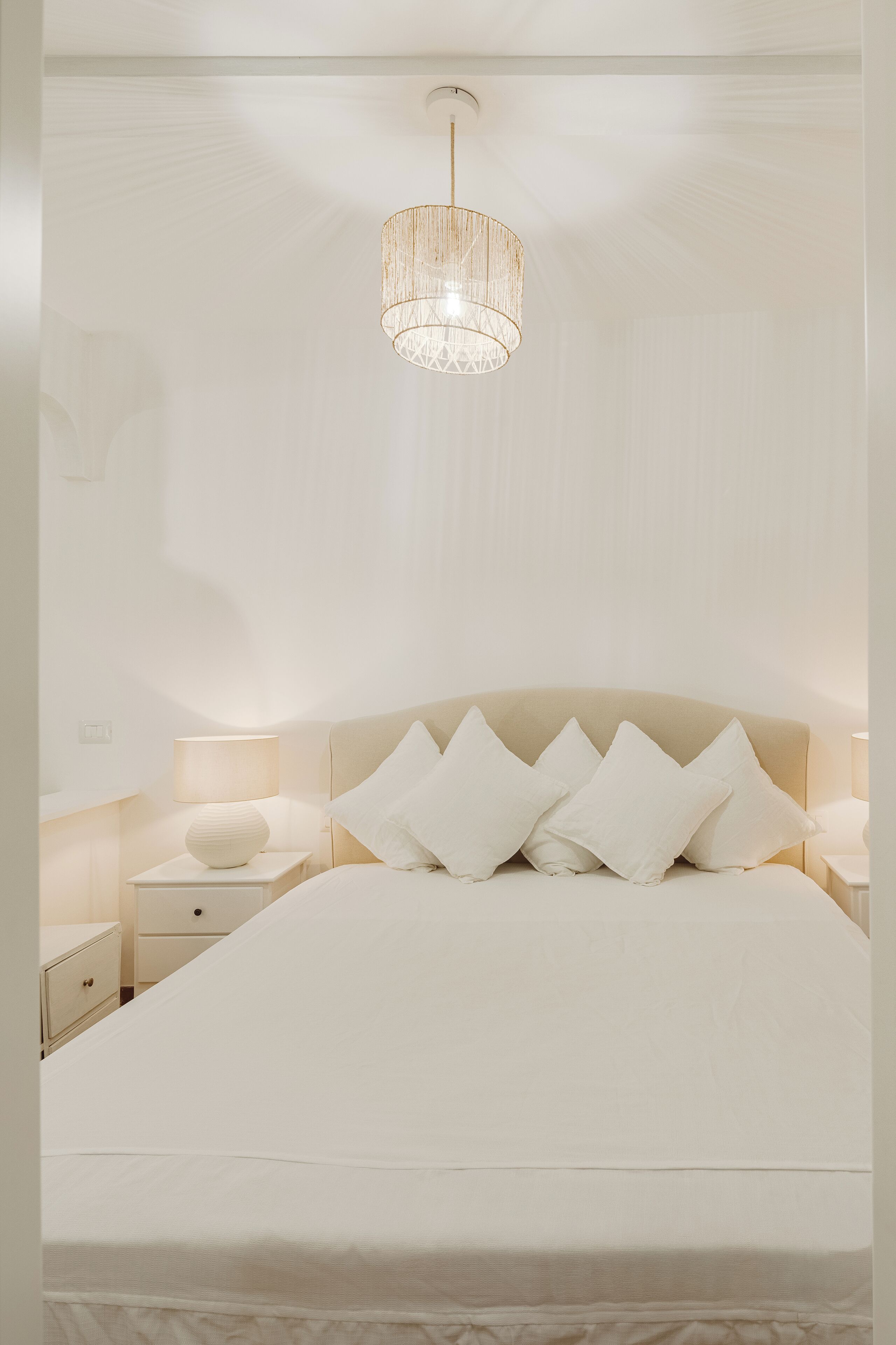 Una camera da letto con un letto grande, un comodino, una lampada e una lampada a sospensione.