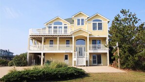 A two-story building with a balcony on the upper floor, a front entrance, and a small porch area. - Sunny 8BR Dog Friendly | Pool | Hot Tub (Corolla)