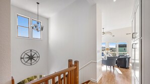 A staircase with wooden railings leading to a living area with a view of the outdoors. - Sunny 8BR Dog Friendly | Pool | Hot Tub (Corolla)