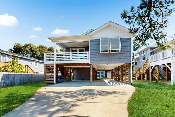 Une maison à deux étages avec un garage fermé, un balcon et une cour arrière clôturée.