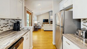 A modern kitchen with white cabinets, a stainless steel refrigerator, and a wooden countertop. - KDN4512: Sandy Feet Retreat | Dog Friendly | Fireplace | Theater Room (Kill Devil Hills)