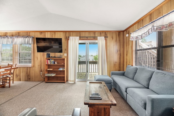 A cozy living room with a sofa, a coffee table, a TV, and a bookshelf.