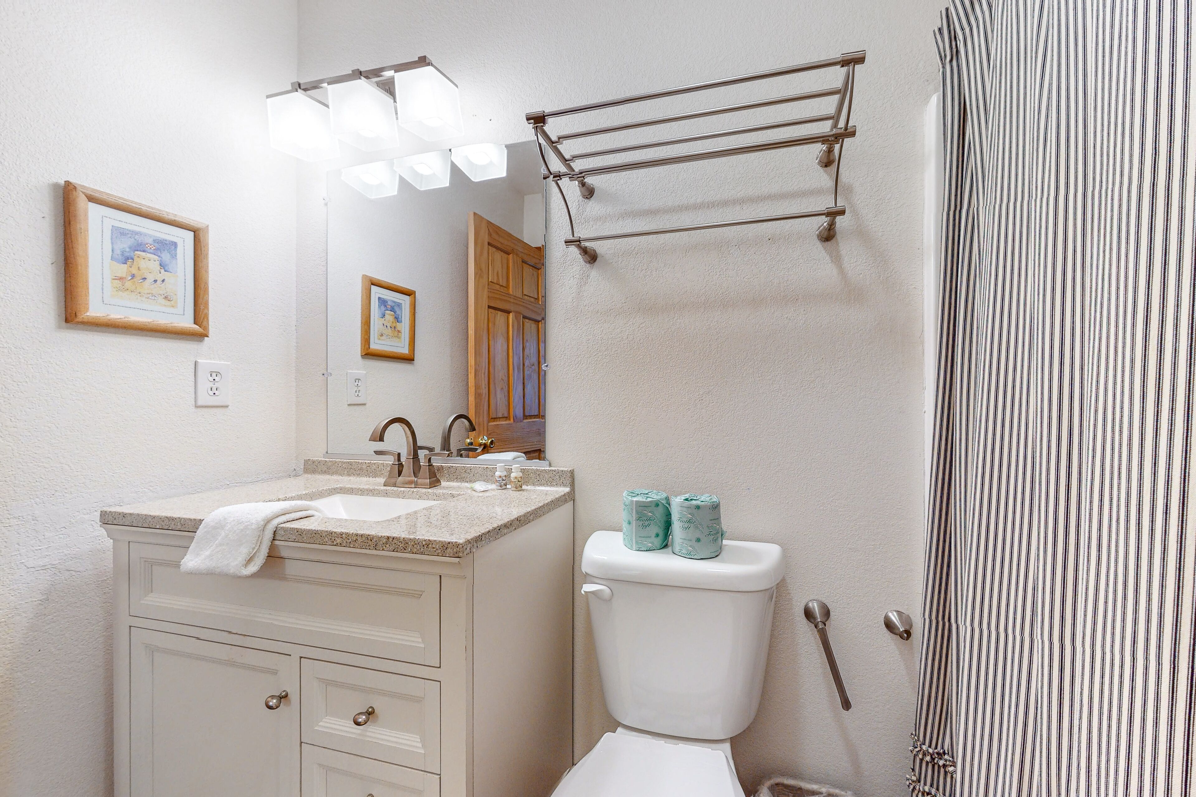A bathroom with a sink, toilet, and shower curtain.
