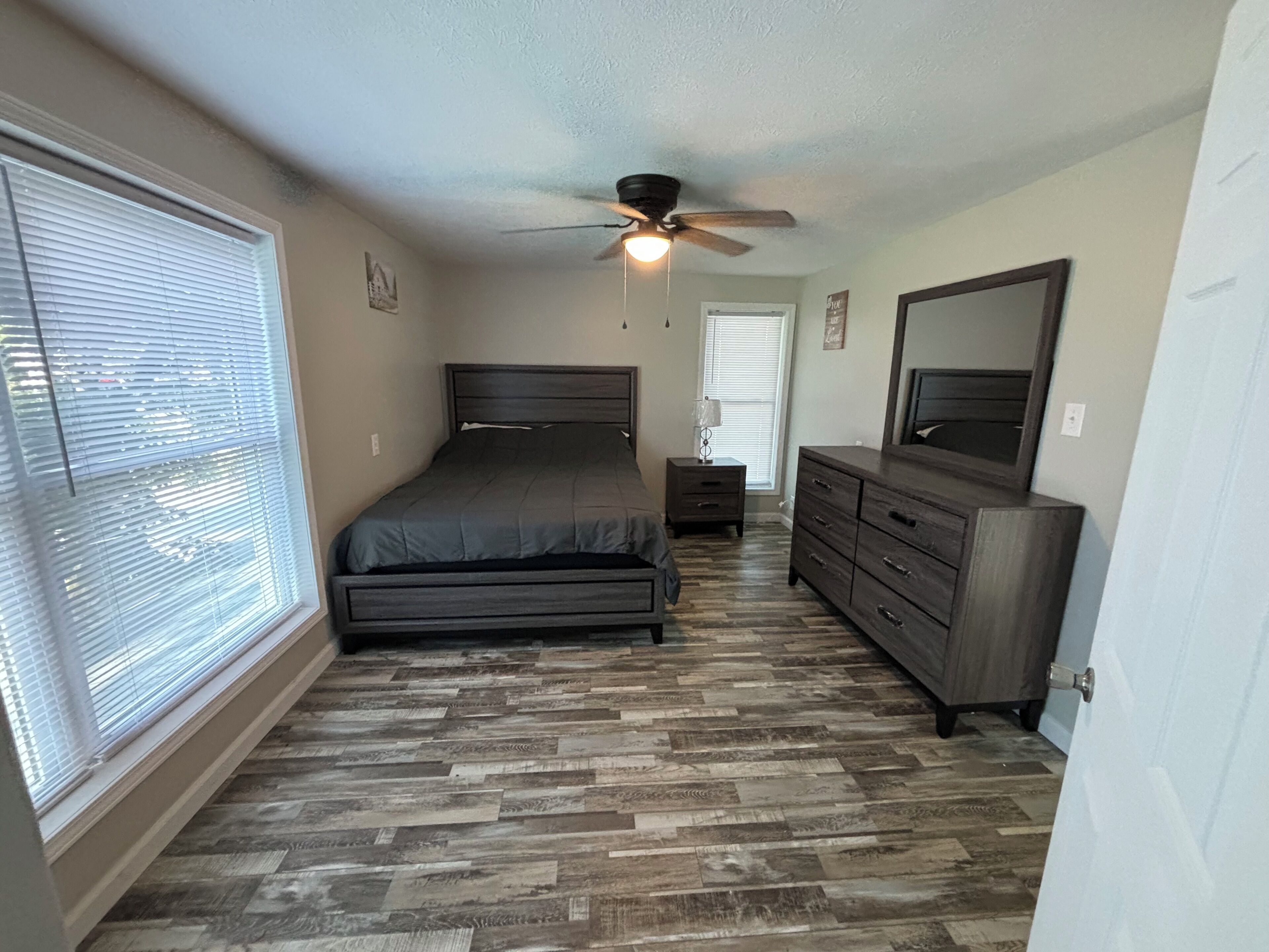 A bedroom with a bed, dresser, nightstand, and ceiling fan.