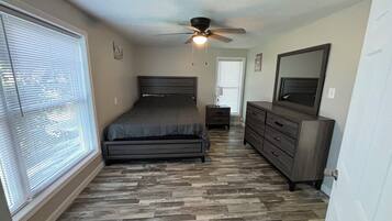 A bedroom with a bed, dresser, nightstand, and ceiling fan.