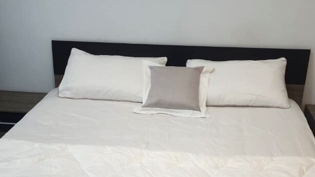 Un lit avec une couette blanche matelassée et deux oreillers.