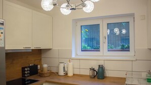 Una cocina con armarios blancos, encimera de madera, cocina por inducción Bosch y ventana con vista a zonas verdes.
