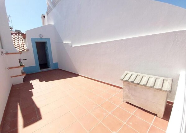 A narrow outdoor corridor with a tiled floor, a blue door, and a radiator. - The Beach House - Duna Parque Resorts & Hotels (Odemira)
