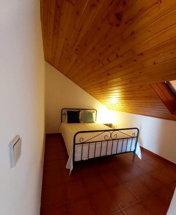 A small, cozy room with a sloped wooden ceiling and a single bed with a metal frame. - The Beach House - Duna Parque Resorts & Hotels (Odemira)