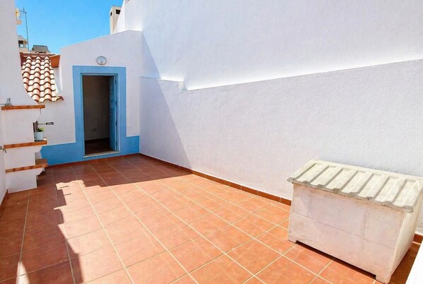 A rooftop terrace with a white wall, a blue door, and a white radiator. - The Beach House - Duna Parque Group (Odemira)