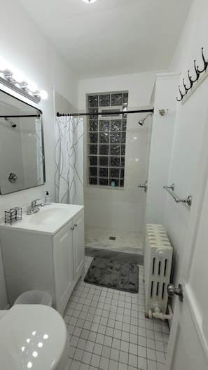 Un baño con lavamanos, espejo e inodoro blancos.