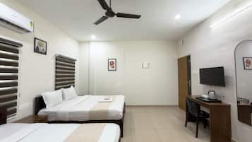 Quarto de hotel com duas camas, uma escrivaninha, televisão e ventoinha no teto.