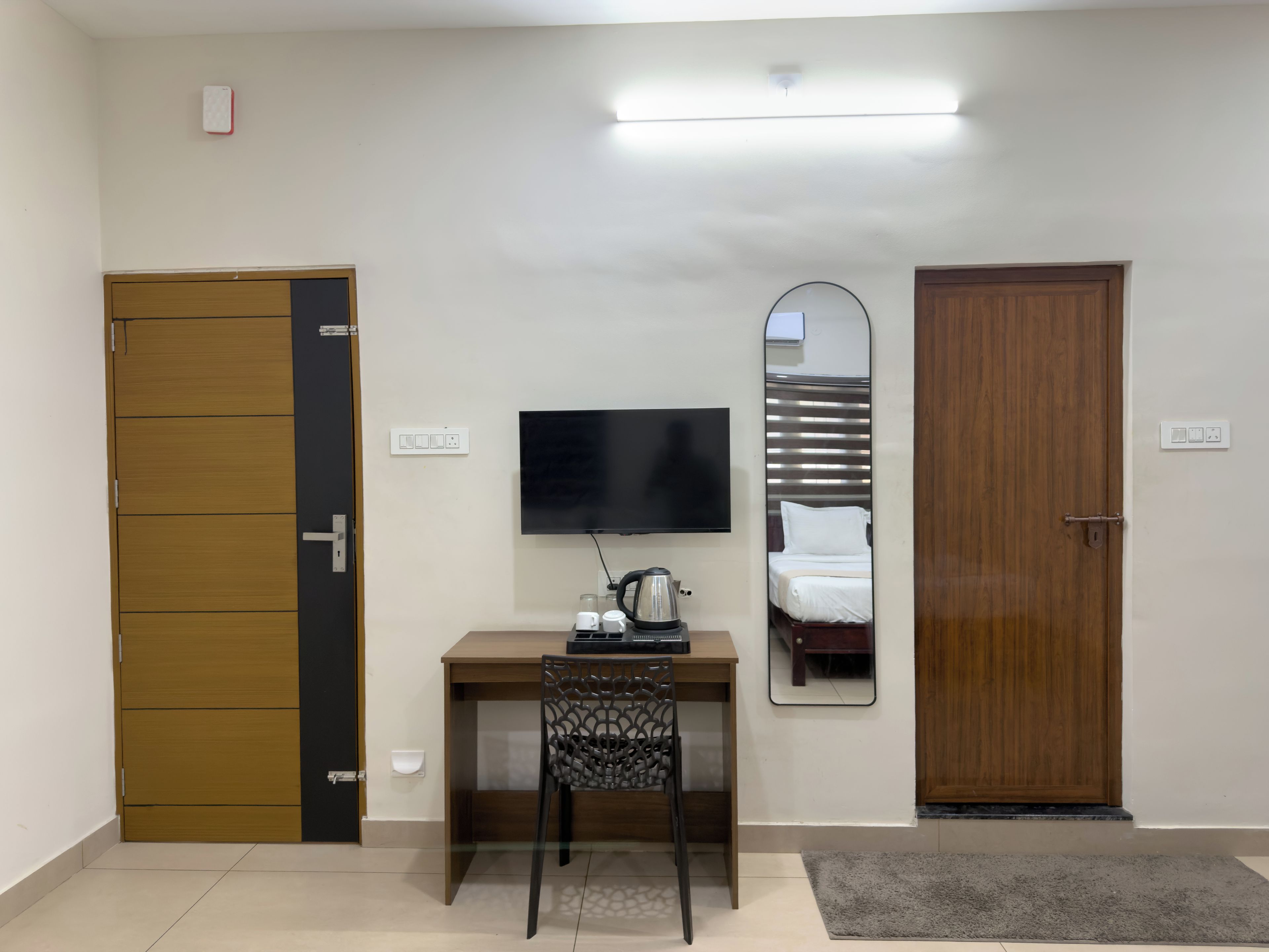 Habitación de hotel con escritorio, silla, televisión y dos puertas.