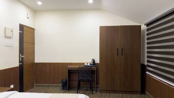 Una habitación de hotel con una cama, un escritorio, una silla, un armario y una puerta corredera.