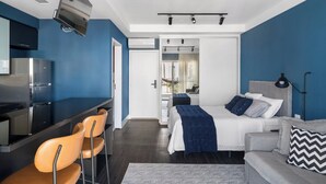 A modern bedroom with a bed, bedside table, and a desk with chairs. - Studio - Campo Belo with Metro in Front and Rooftop with Sunset. (Brooklin São Paulo)