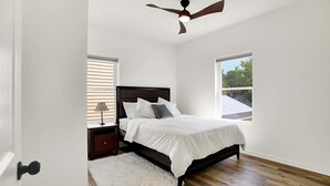Un dormitorio con cama, mesita de noche, lámpara y ventilador de techo.