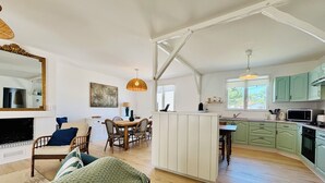 A spacious living area with a dining table, a sofa, and a kitchen with green cabinets.