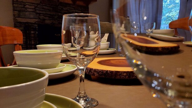 A dining table set with plates, bowls, and a wine glass, with a television in the background.