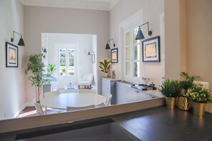 Una cocina moderna con comedor, que incluye una mesa redonda grande, sillas blancas y plantas en macetas.