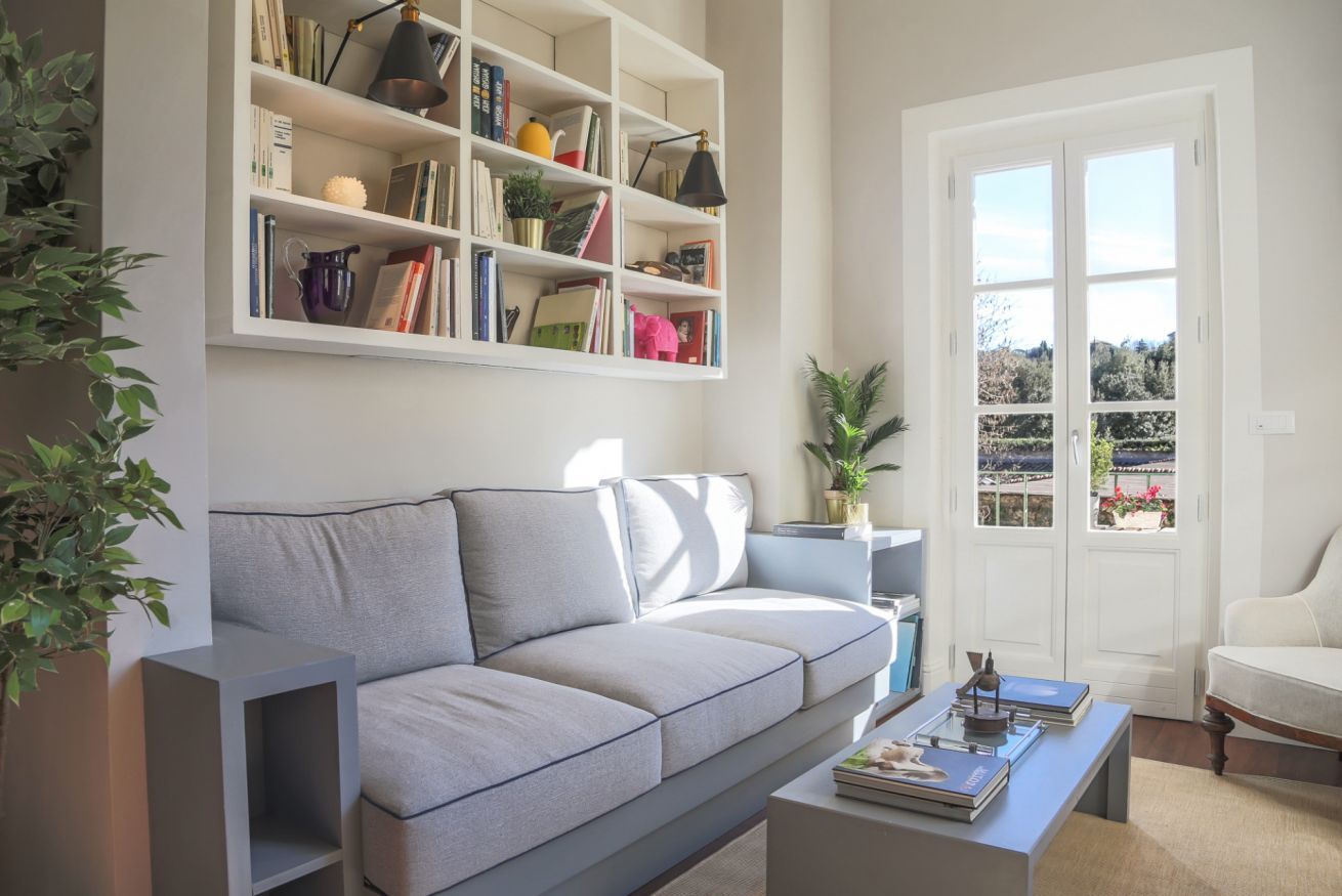A living room with a grey sofa, a bookshelf, and a coffee table.