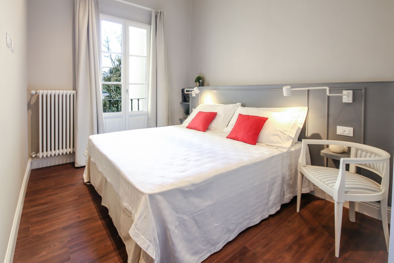Ein ordentlich eingerichtetes Schlafzimmer mit einem großen Bett, einem Sessel, einem Nachttisch und einer Heizung.