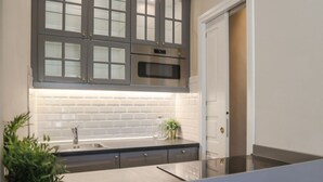 Une cuisine moderne avec des meubles gris, un four en acier inoxydable et un dosseret de carrelage blanc.
